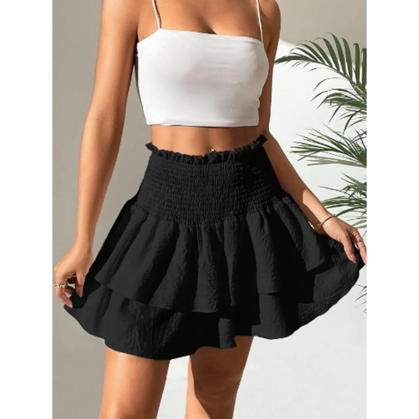 Person wearing a white top and black skirt with a neutral background