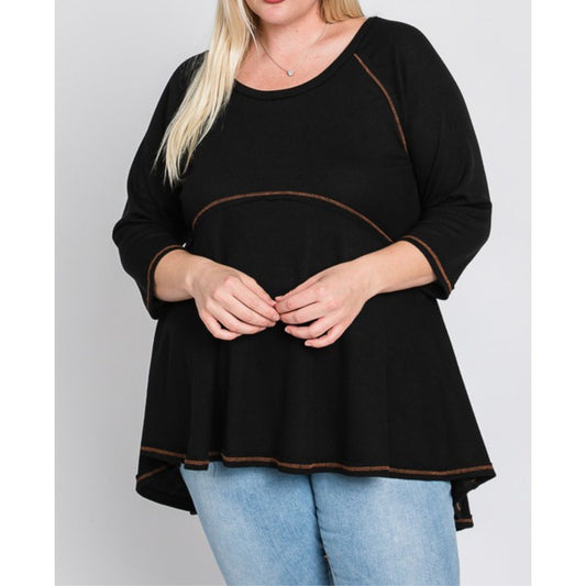 Black top with brown trim worn by a person on a gray background