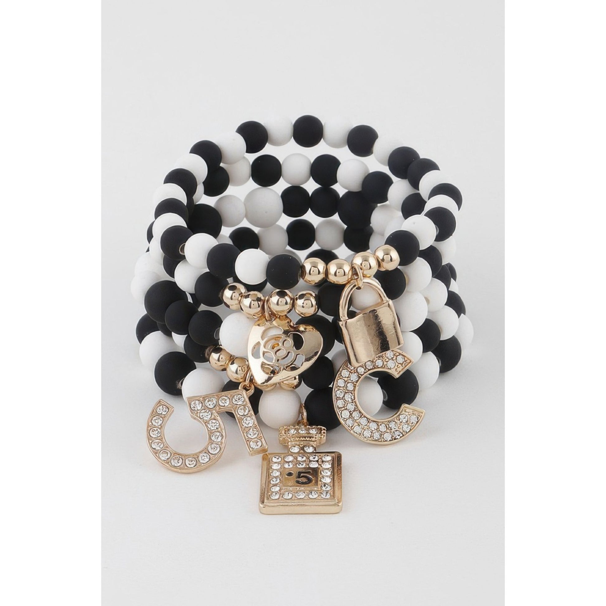 Black and white beaded bracelet with gold charms on a light gray background