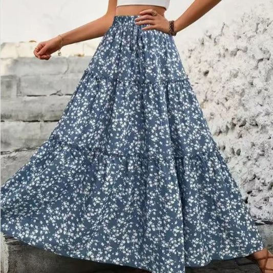 Person wearing a blue floral skirt with a stone wall background