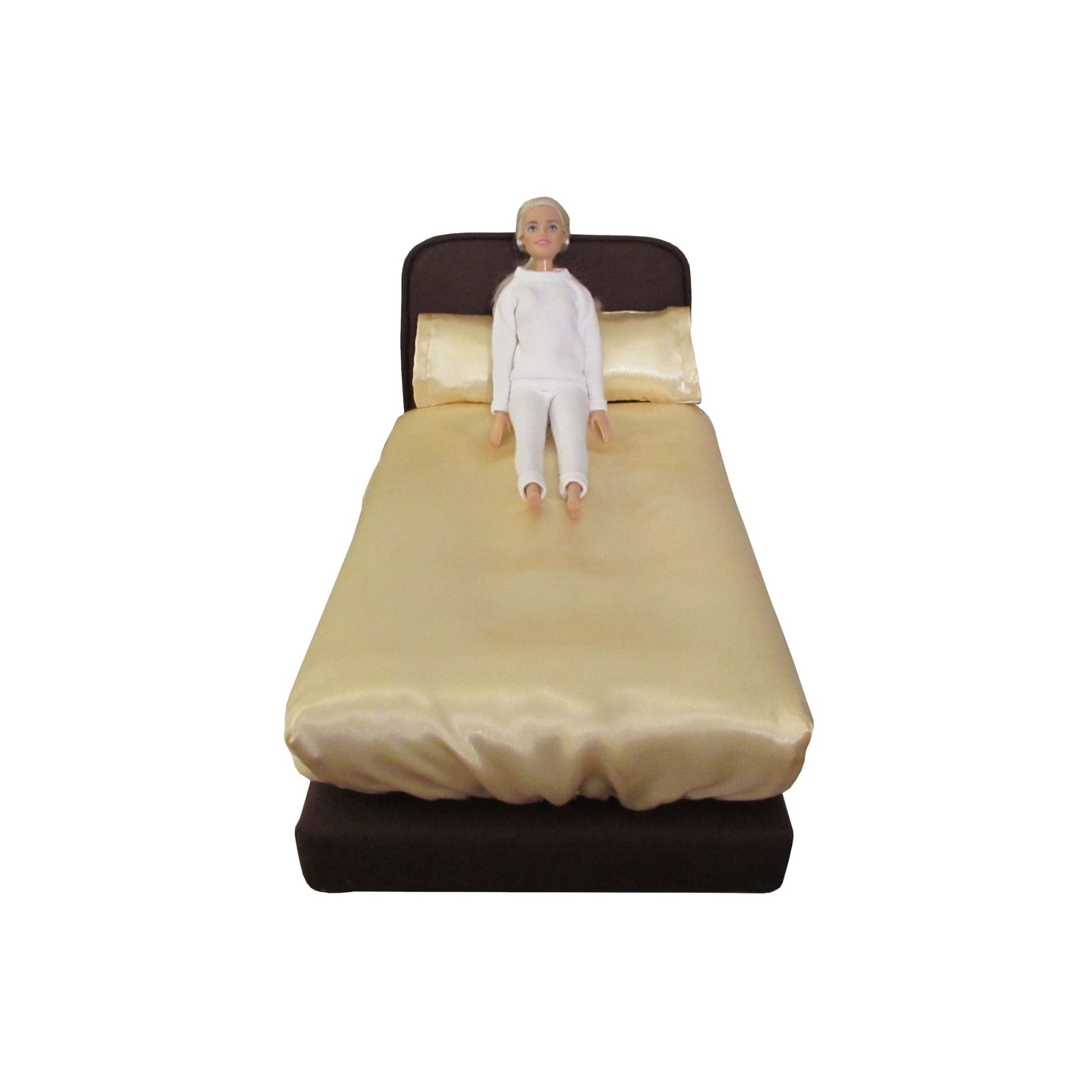 11.5-inch doll wearing a white sweatsuit sitting on a brown doll bed with light yellow pillowcases and fitted sheet