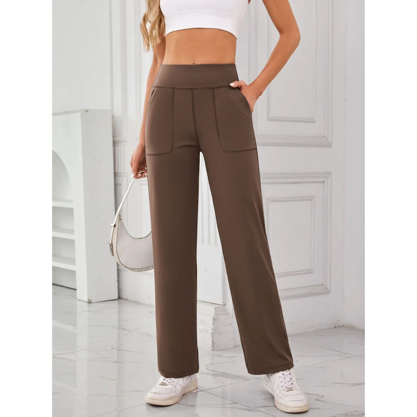 Person wearing brown pants and white sneakers in a minimalistic setting
