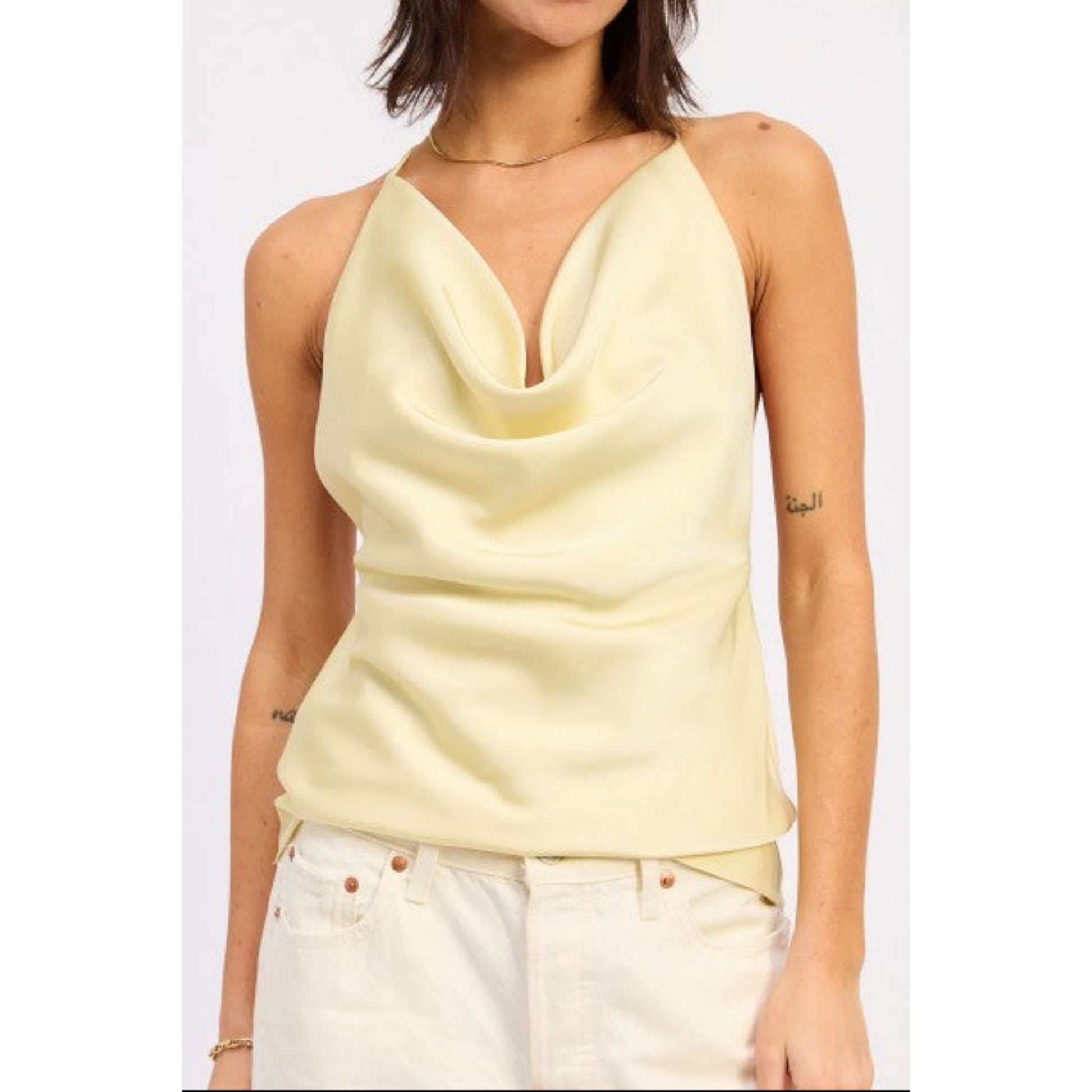 Woman wearing a light yellow sleeveless top on a white background