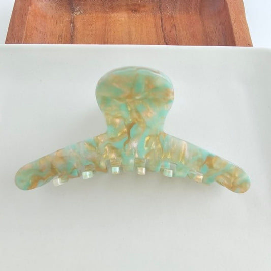 Marbled green and gold hair clip on a white background