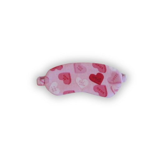 Pink sleep mask with heart patterns on a white background