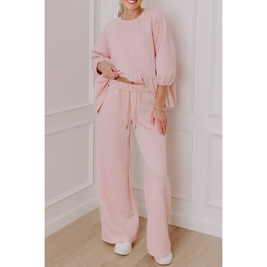 Person wearing a pink textured outfit in a minimalistic room.