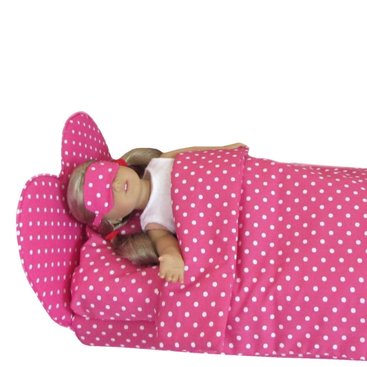Doll lying on a pink polka dot bed with matching pillow and blanket.
