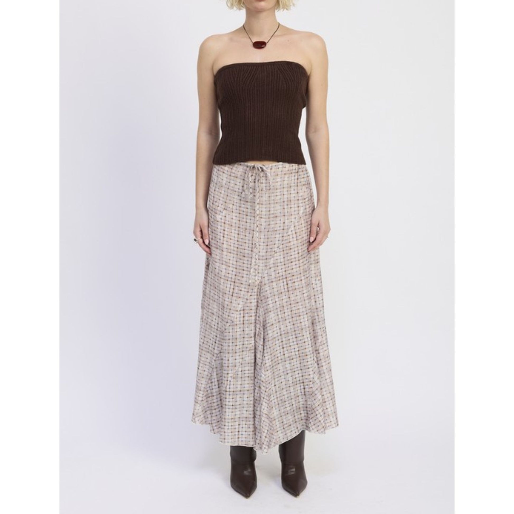 Person wearing a strapless brown top and plaid skirt on a white background