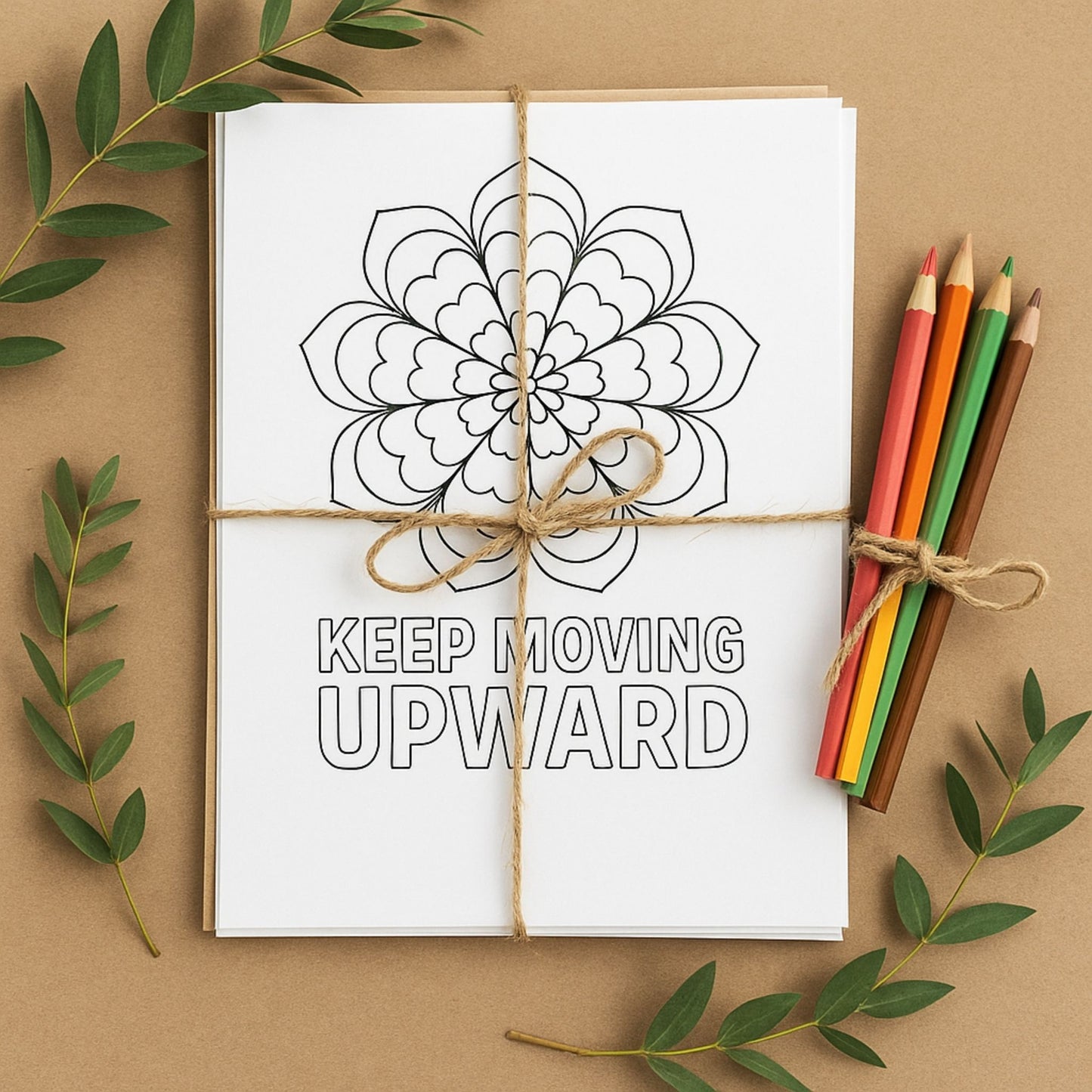 Coloring book with mandala design and 'Keep Moving Upward' text, tied with twine, on a brown background with colored pencils and green leaves.