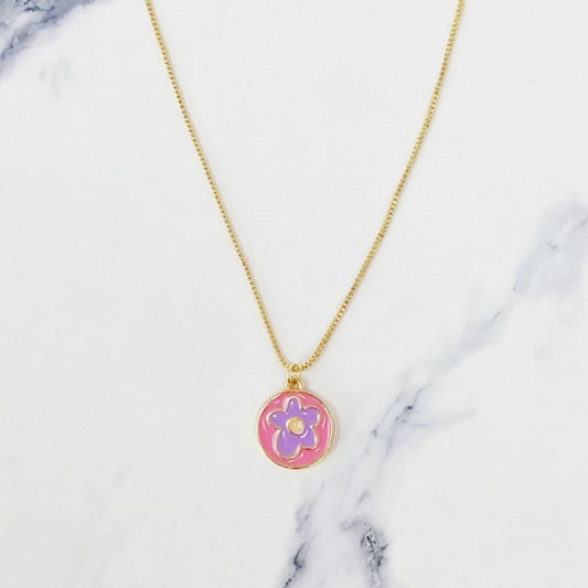 Gold necklace with a colorful flower pendant on a marble background