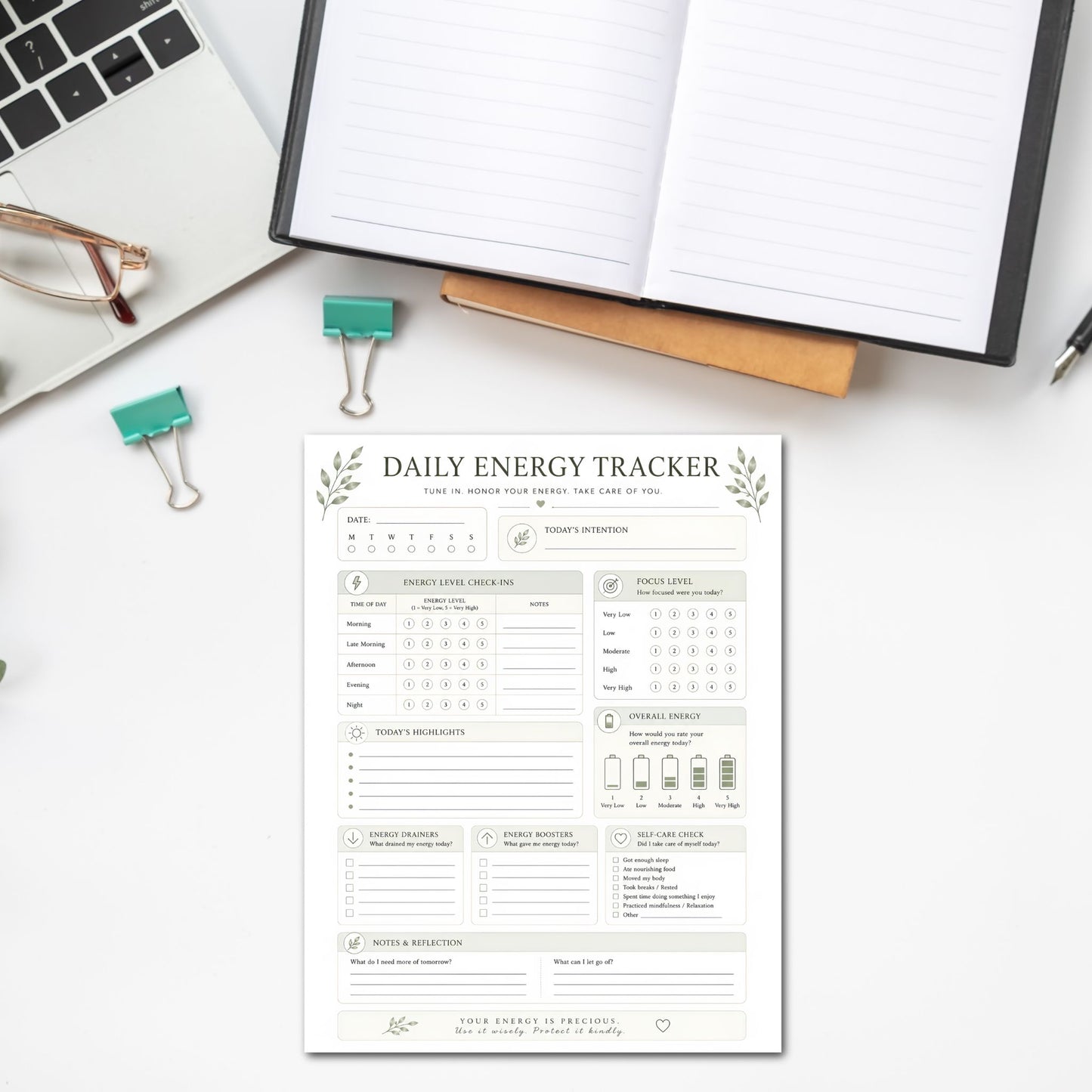 Daily energy tracker sheet on a desk with a laptop and glasses.