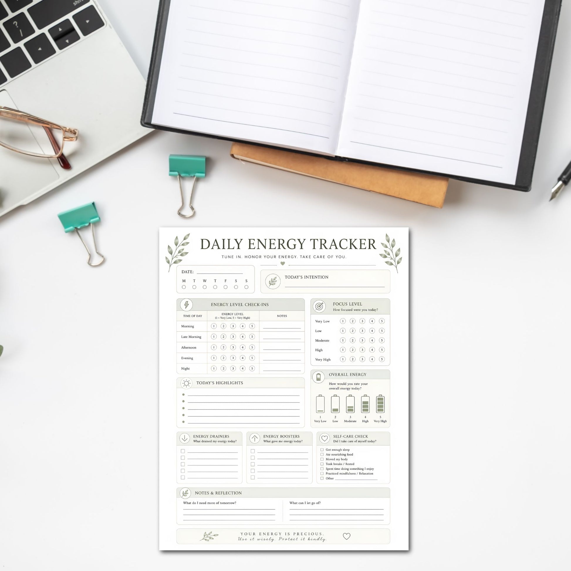 Daily energy tracker sheet on a desk with a laptop and glasses.