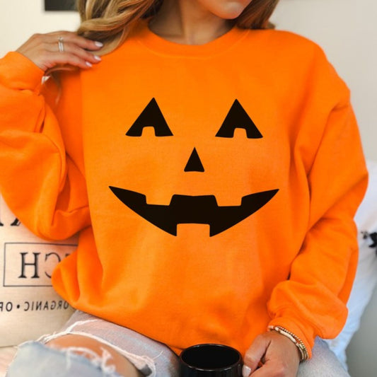 Person wearing an orange sweatshirt with a black pumpkin face design.