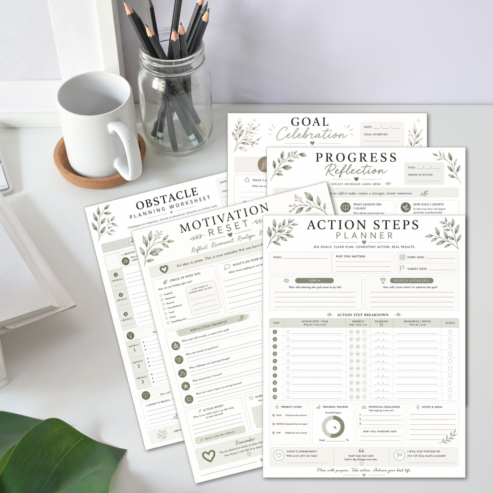 Two planner sheets on a desk with a mug and pencils in the background