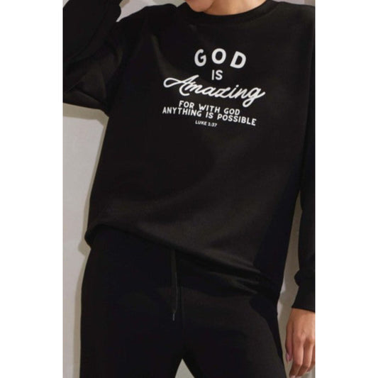 Black sweatshirt with 'God is Amazing' text worn by a person