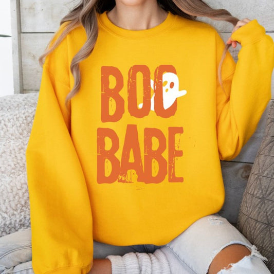 Person wearing a yellow sweatshirt with 'BOO BABE' text, sitting on a couch.