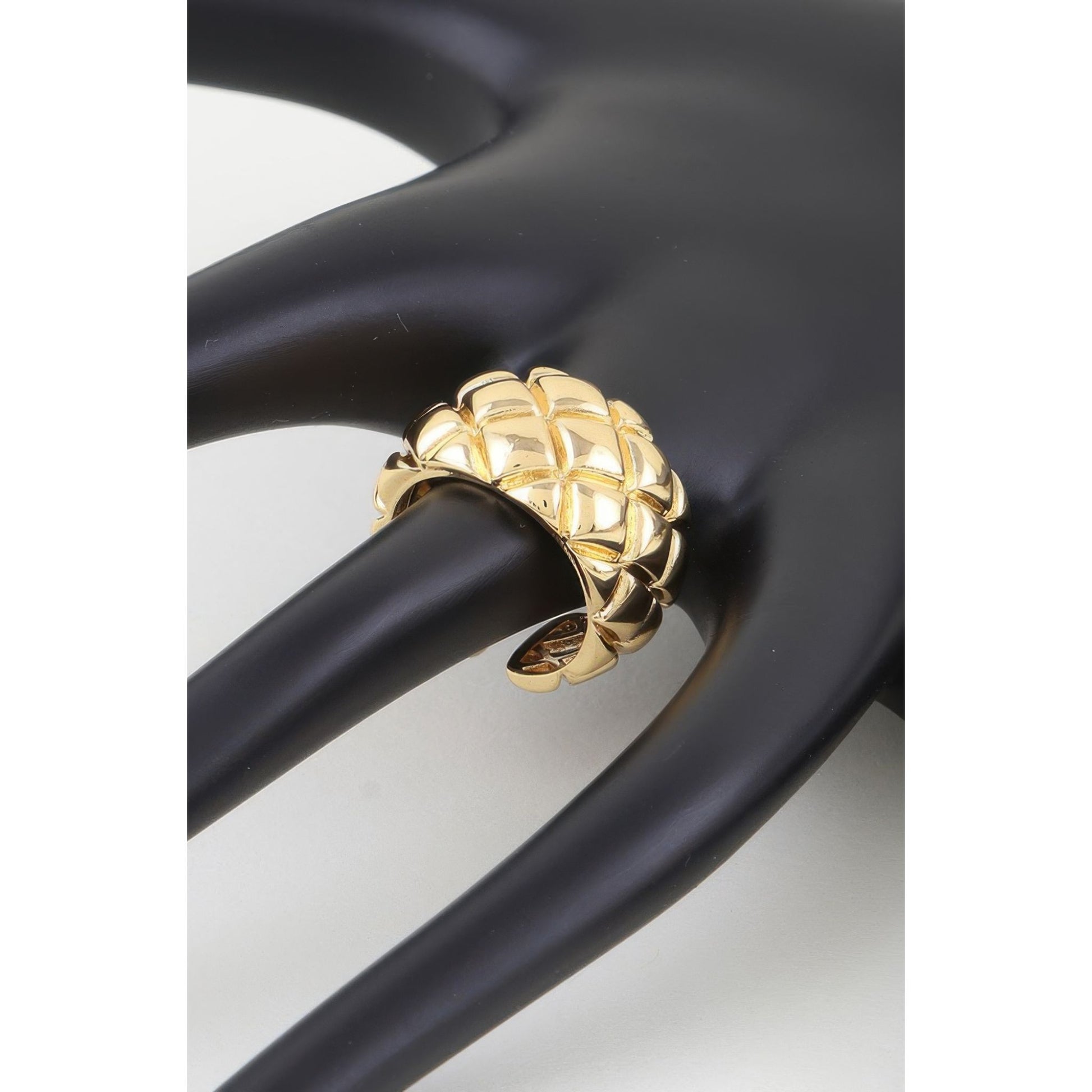 Gold ring with a textured design on a black stand