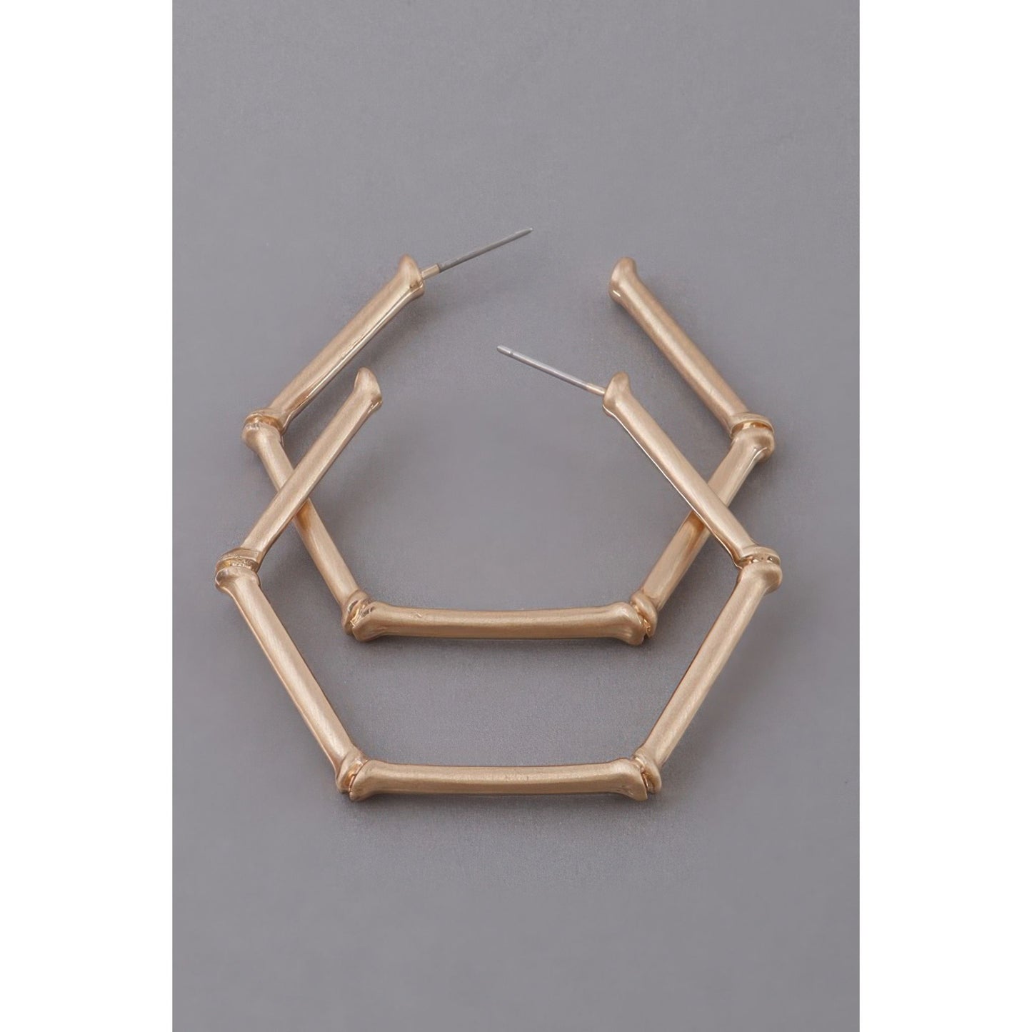 Gold geometric hoop earrings on a gray background