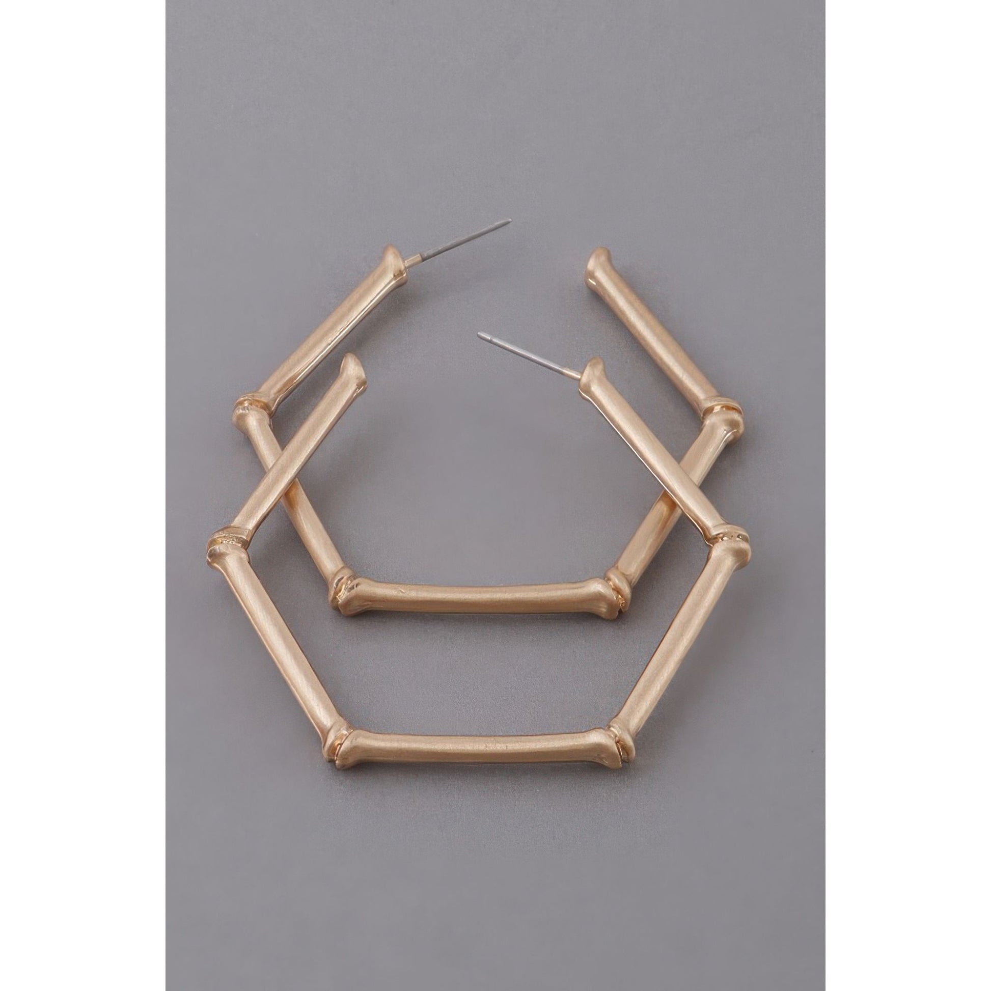 Gold geometric hoop earrings on a gray background