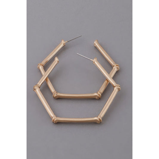 Gold geometric hoop earrings on a gray background