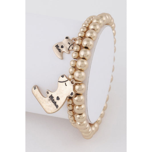 Gold beaded bracelet with dog-shaped charms on a light gray background