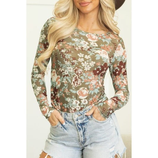 Woman wearing a floral long-sleeve top and denim shorts on a white background
