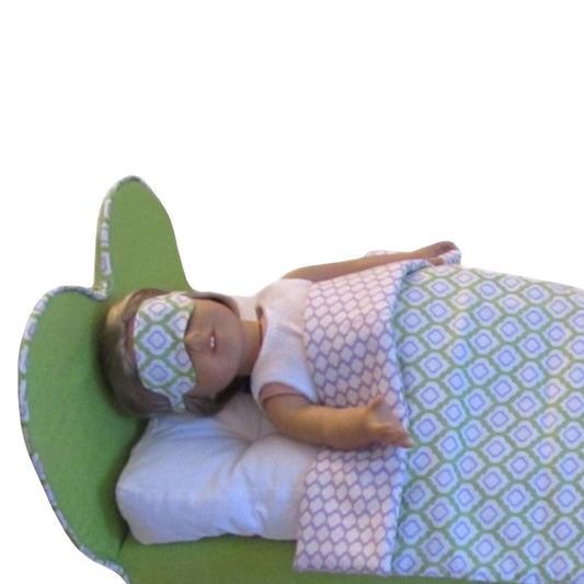 An 18-inch doll wearing a green print sleep mask while lying a heart doll bed.