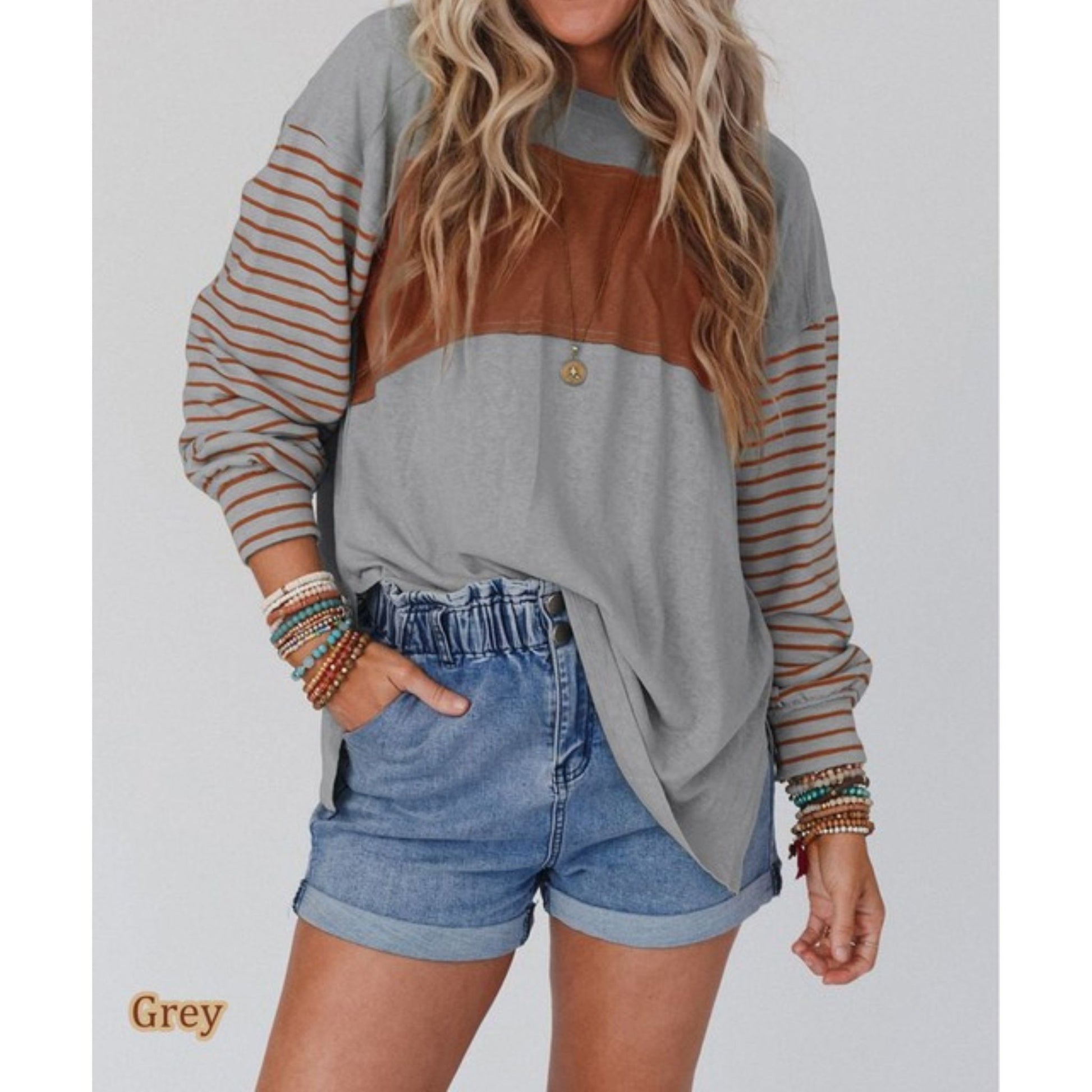 Woman wearing a color-blocked long-sleeve top and denim shorts on a plain background