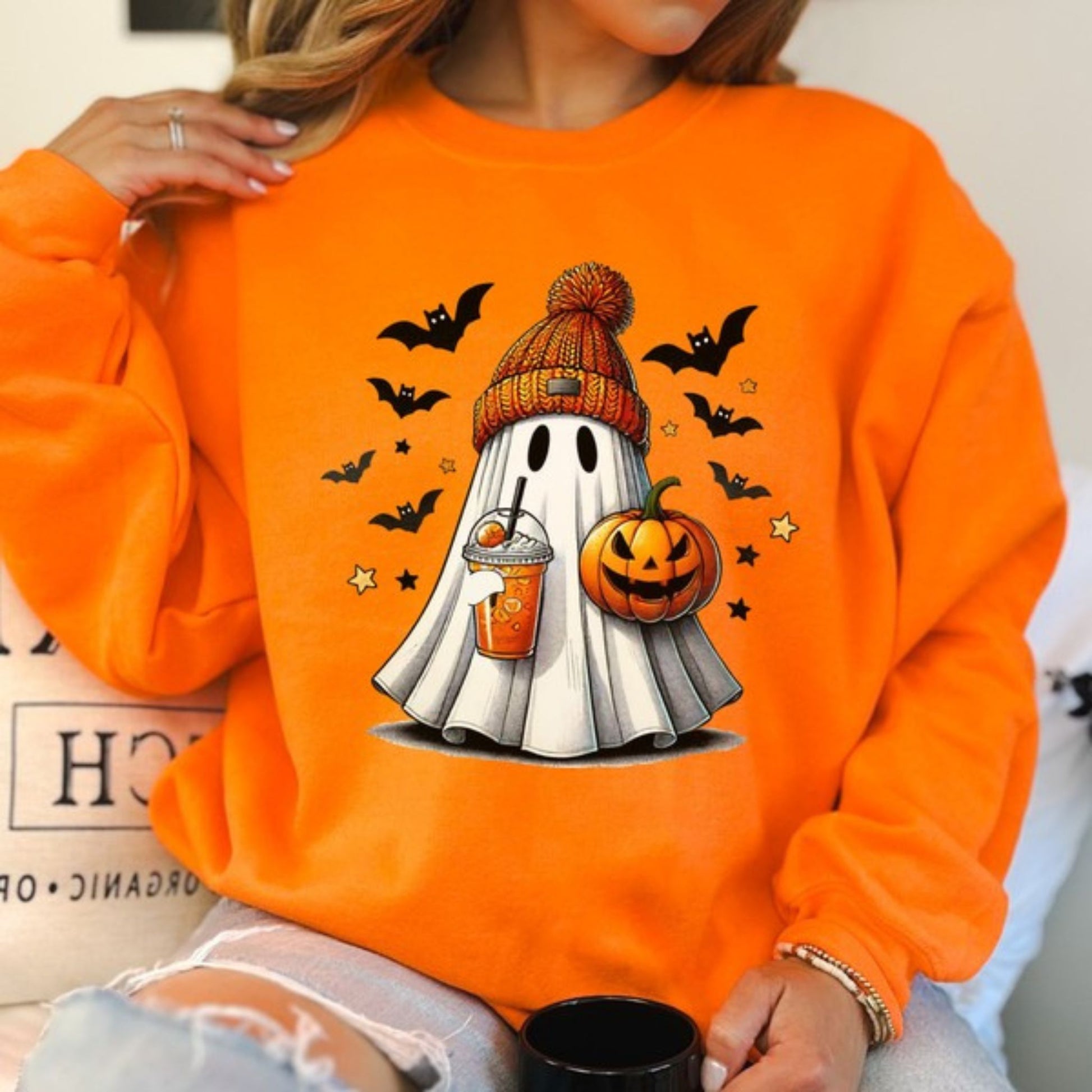 Person wearing an orange sweatshirt with a Halloween-themed ghost design.