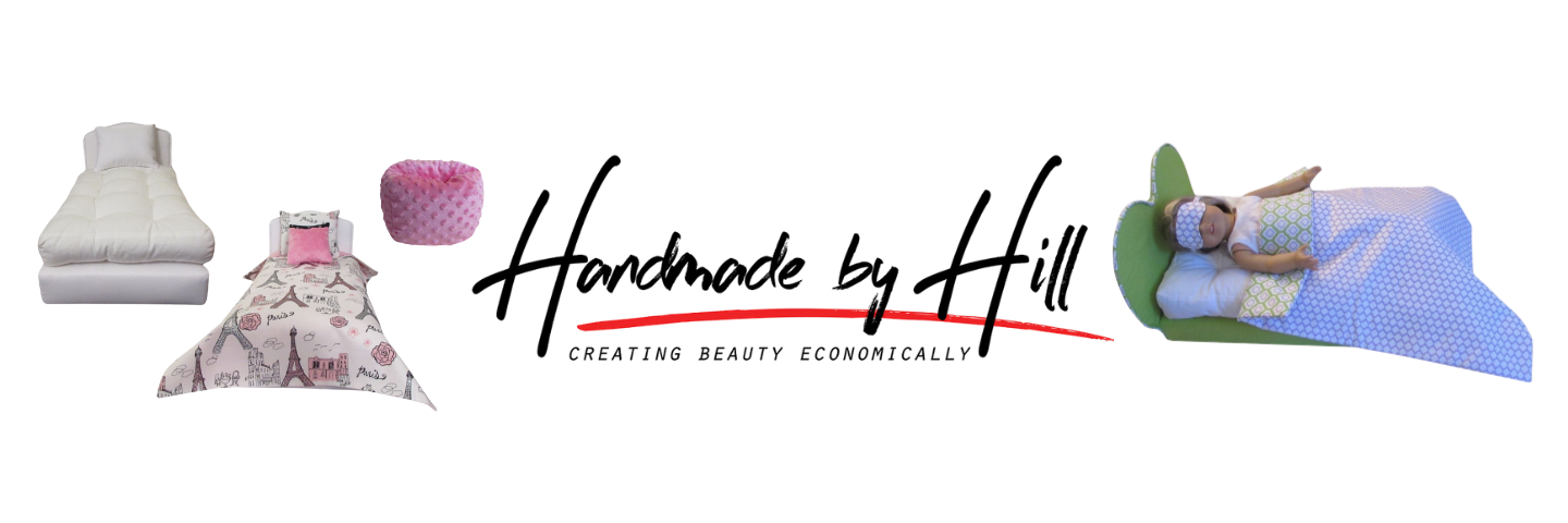 A wide banner-style product collage on a white background showing several bedding and home decor items: a white folded bed or mattress, a pink patterned pillow, a pink cylindrical cushion, a floral fabric piece, and a child lying on a green mattress with a blue patterned blanket. Large script text reads 'Handmade by Hill' with smaller text 'Creating Beauty Economically' across the center.