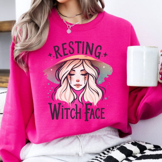 Person wearing a pink sweatshirt with a graphic design and text, holding a mug.