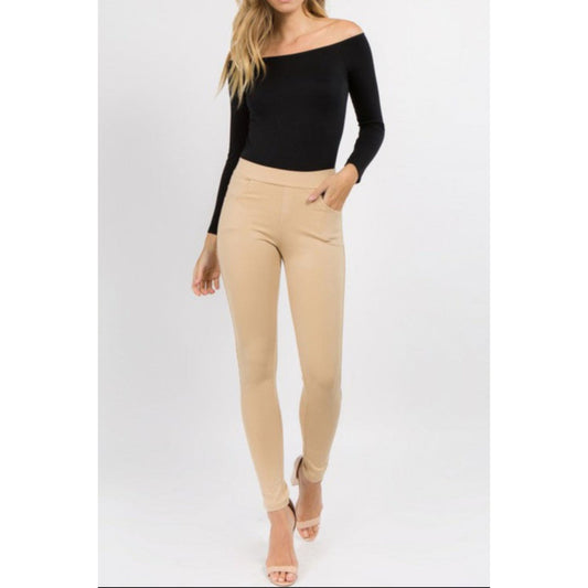 Woman wearing a black off-shoulder top and beige pants on a white background