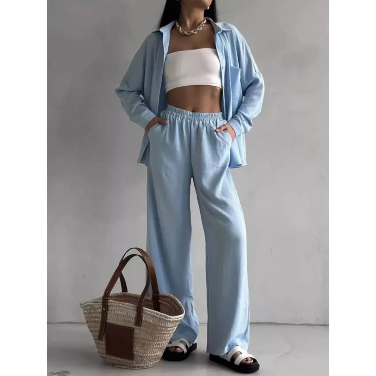 A woman is wearing a light blue relaxed fit shirt and wide leg pants set.