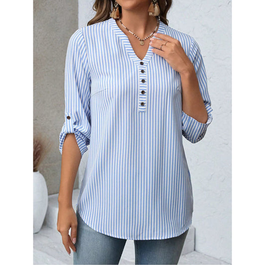 Woman wearing a blue and white striped shirt with rolled-up sleeves against a neutral background