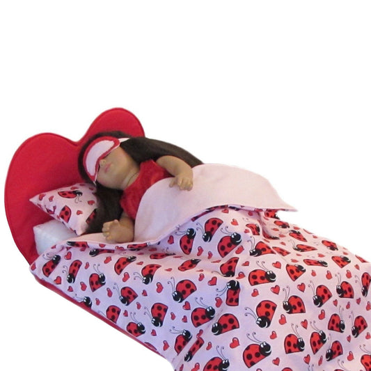 Doll lying in a red and white bed with ladybug pattern