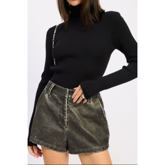 Person wearing a black sweater and green denim shorts on a white background