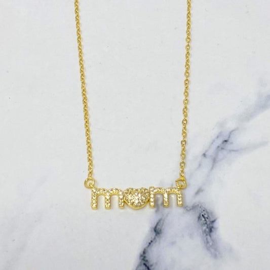 Gold 'mom' necklace on a marble background