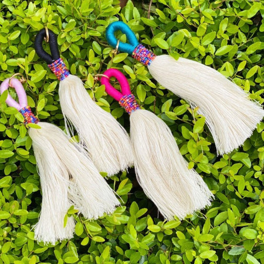 Decorative keychains with tassels on a green leafy background