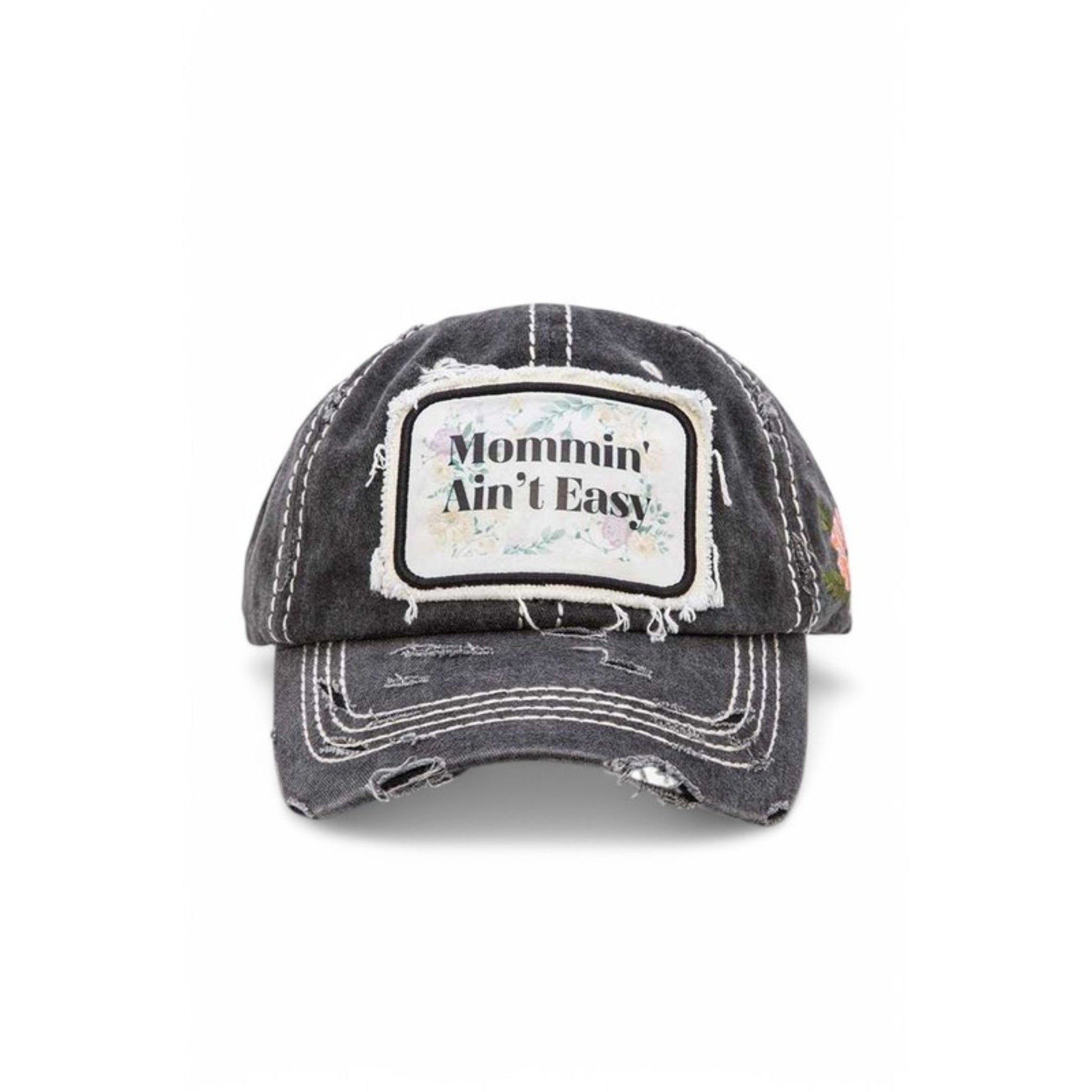 Black distressed baseball cap with 'Mommin' Ain't Easy' patch on a white background
