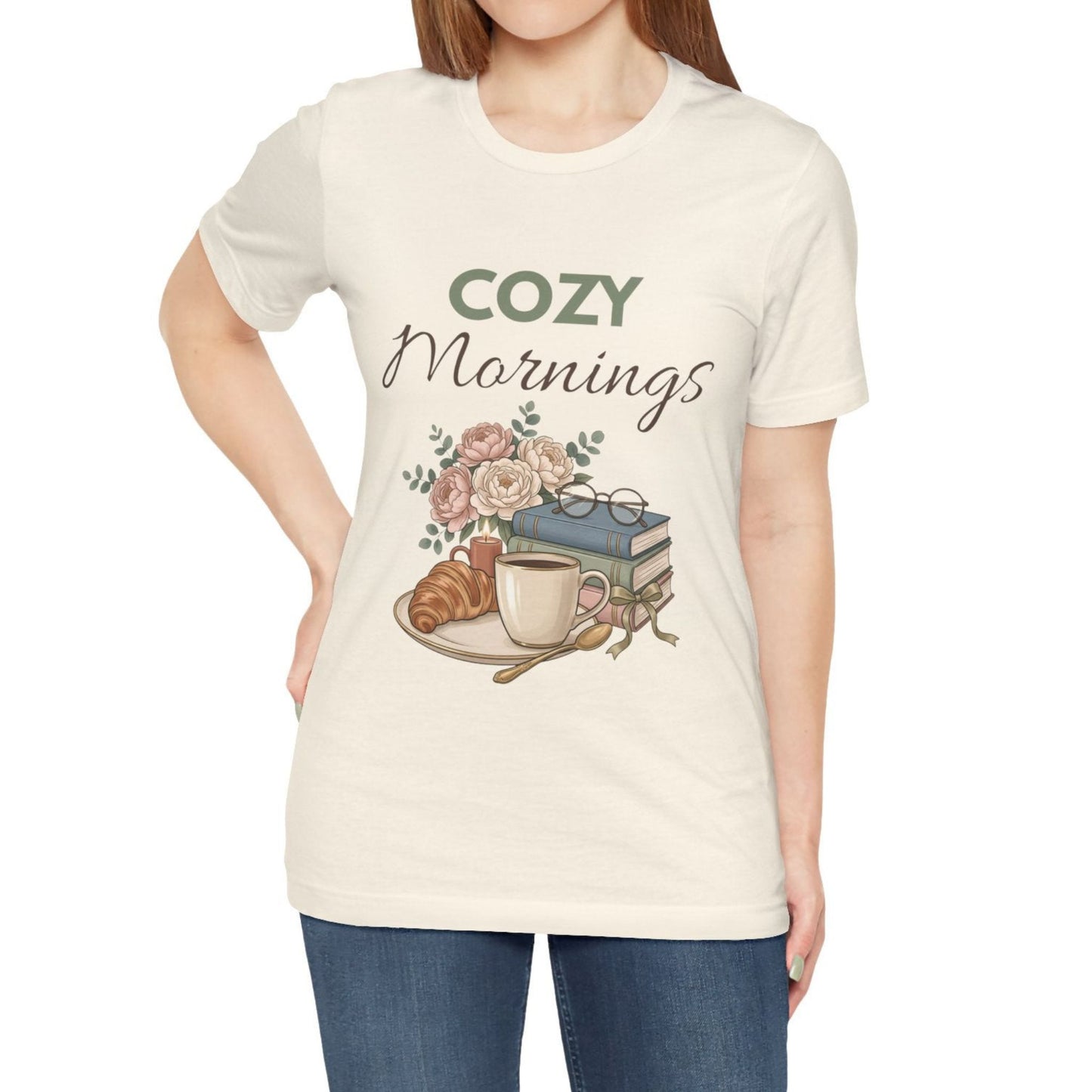 A woman is wearing a natural colored t-shirt with "Cozy Mornings".