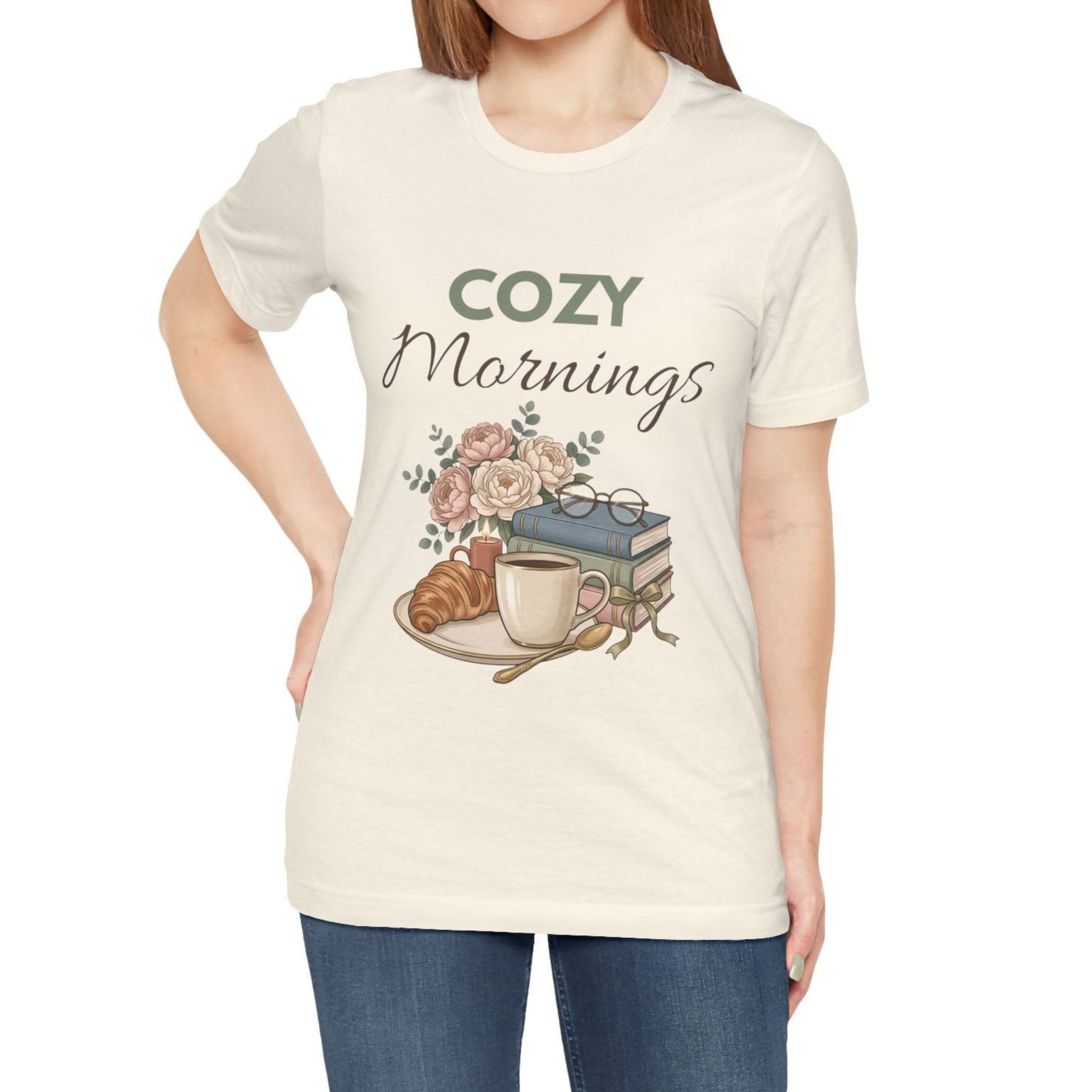 A woman is wearing a natural colored t-shirt with "Cozy Mornings".