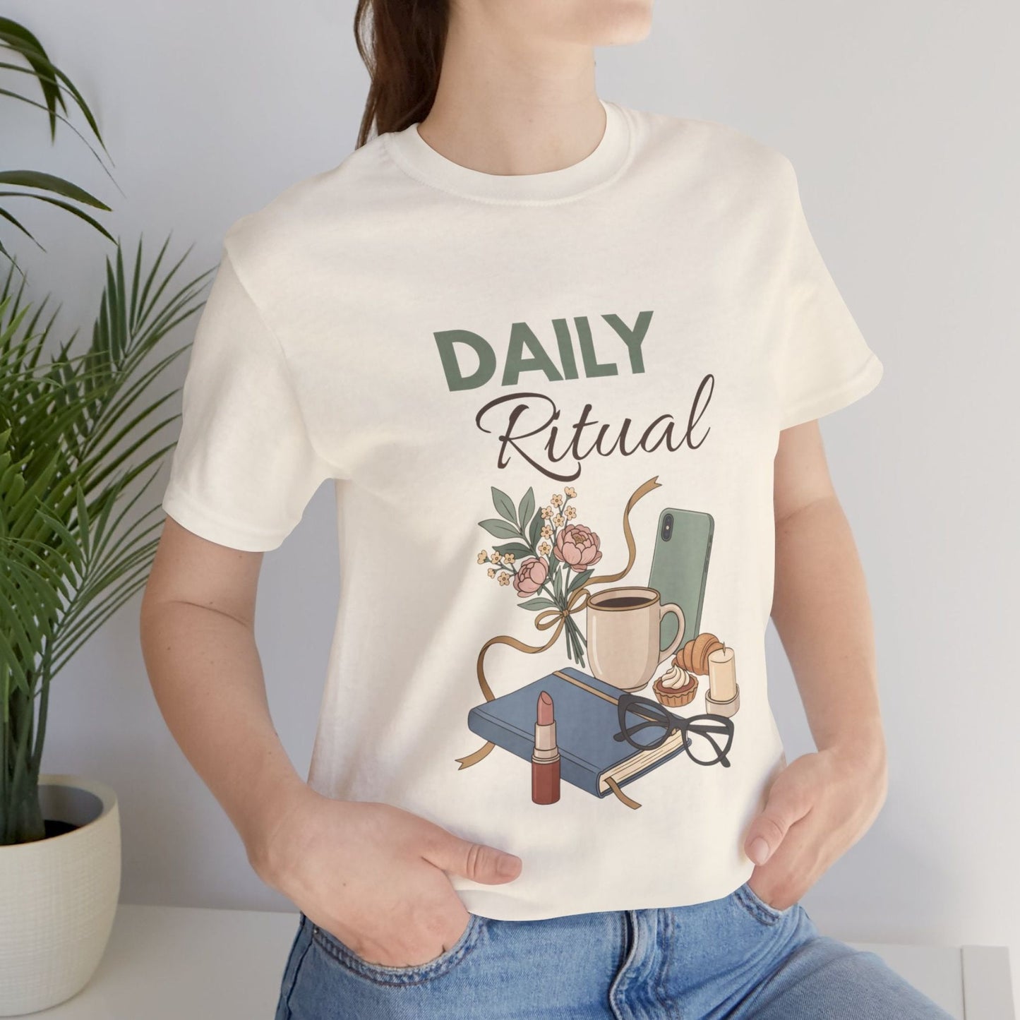 Person wearing a natural colored t-shirt with 'Daily Ritual' design, standing against a plain background.
