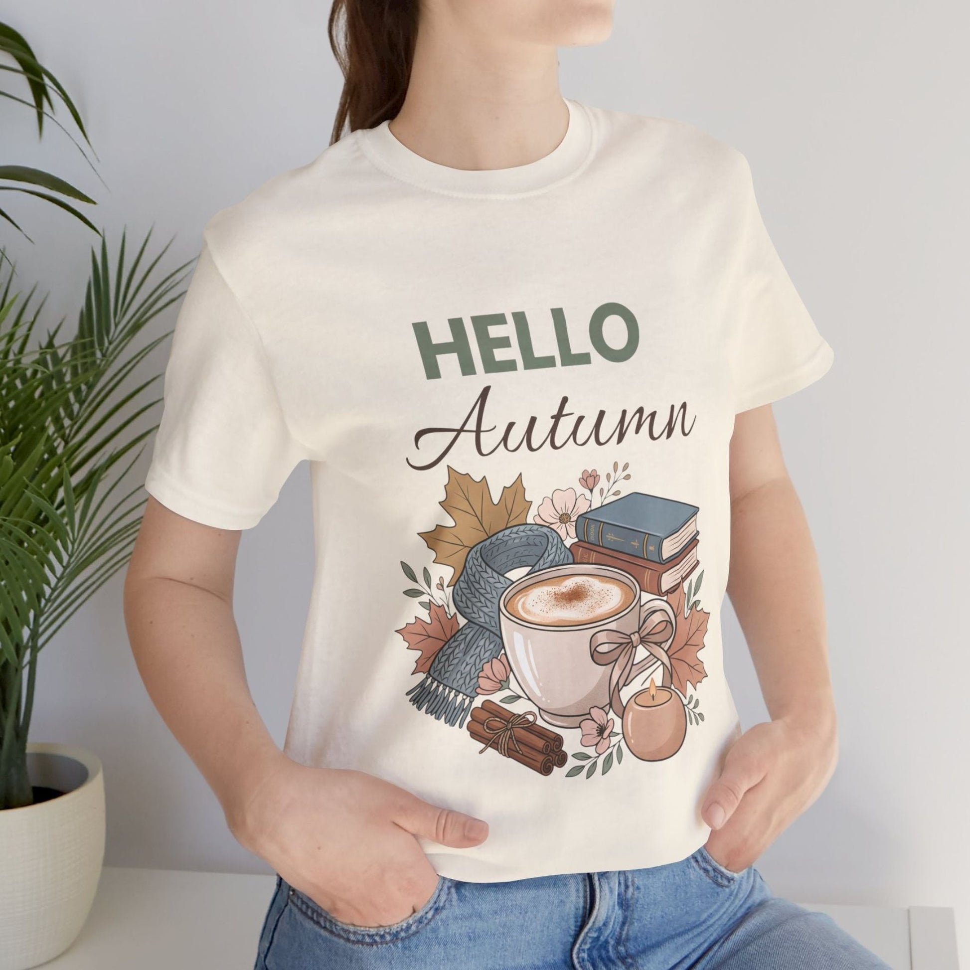 Person wearing a natural colored t-shirt with 'Hello Autumn' design featuring a cup of coffee and autumn elements.
