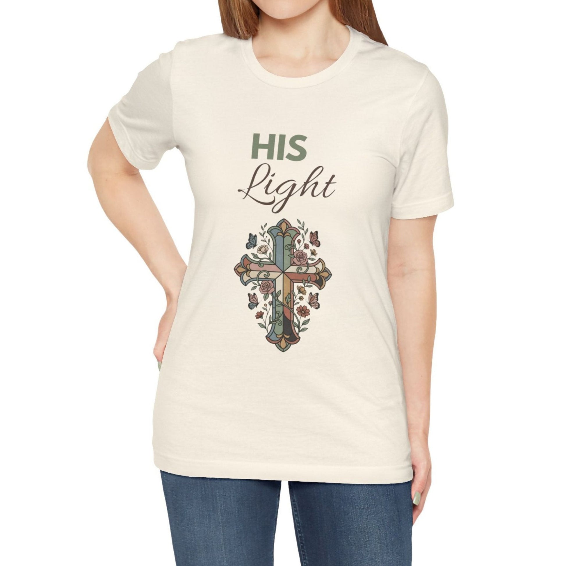 Person wearing a natural colored t-shirt with a cross design and 'HIS Light' text on a white background
