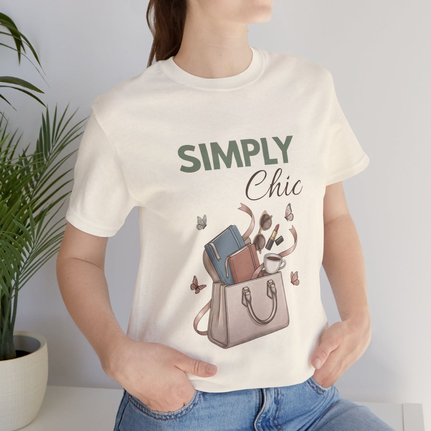 A woman is standing by a plant in a natural colored t-shirt with 'SIMPLY Chic' on the front.