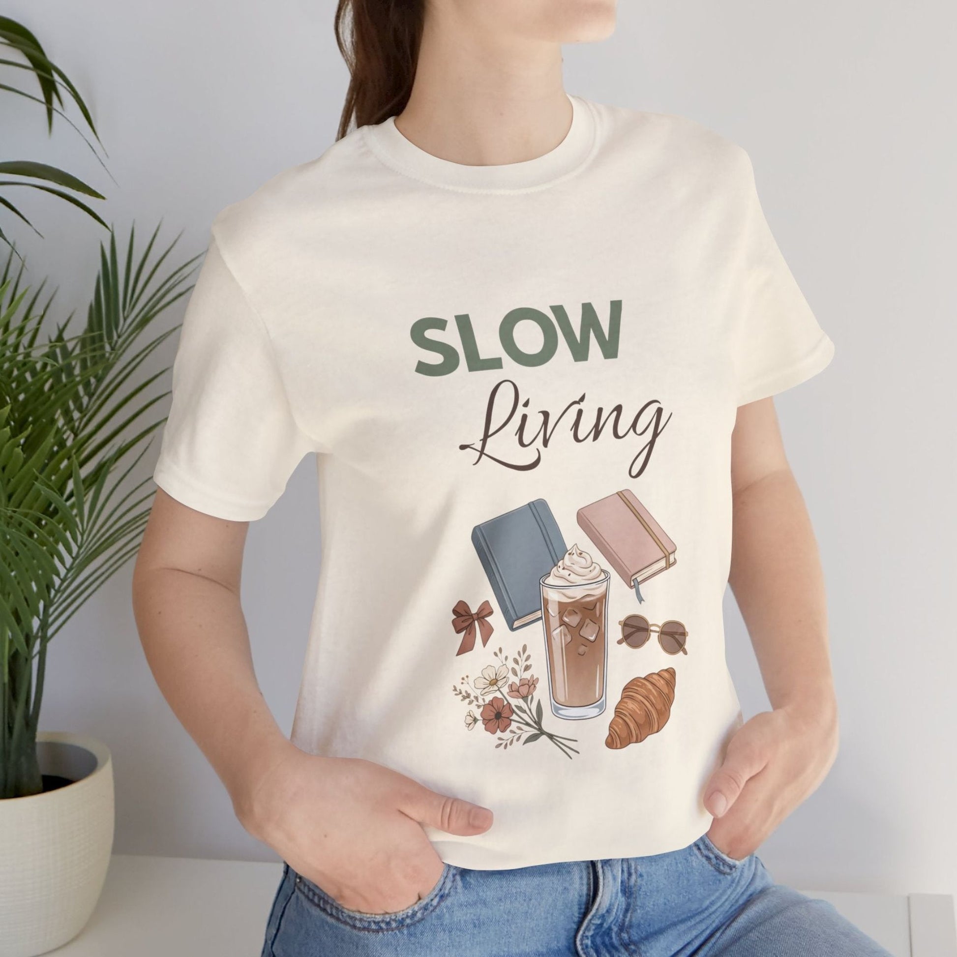 Person wearing a natural colored t-shirt with 'SLOW Living' and lifestyle illustrations.