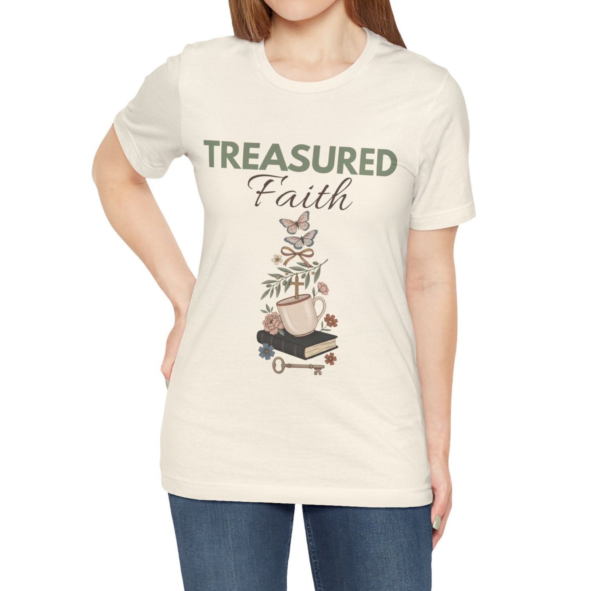 Person wearing a natural colored t-shirt with 'Treasured Faith' design on a plain background