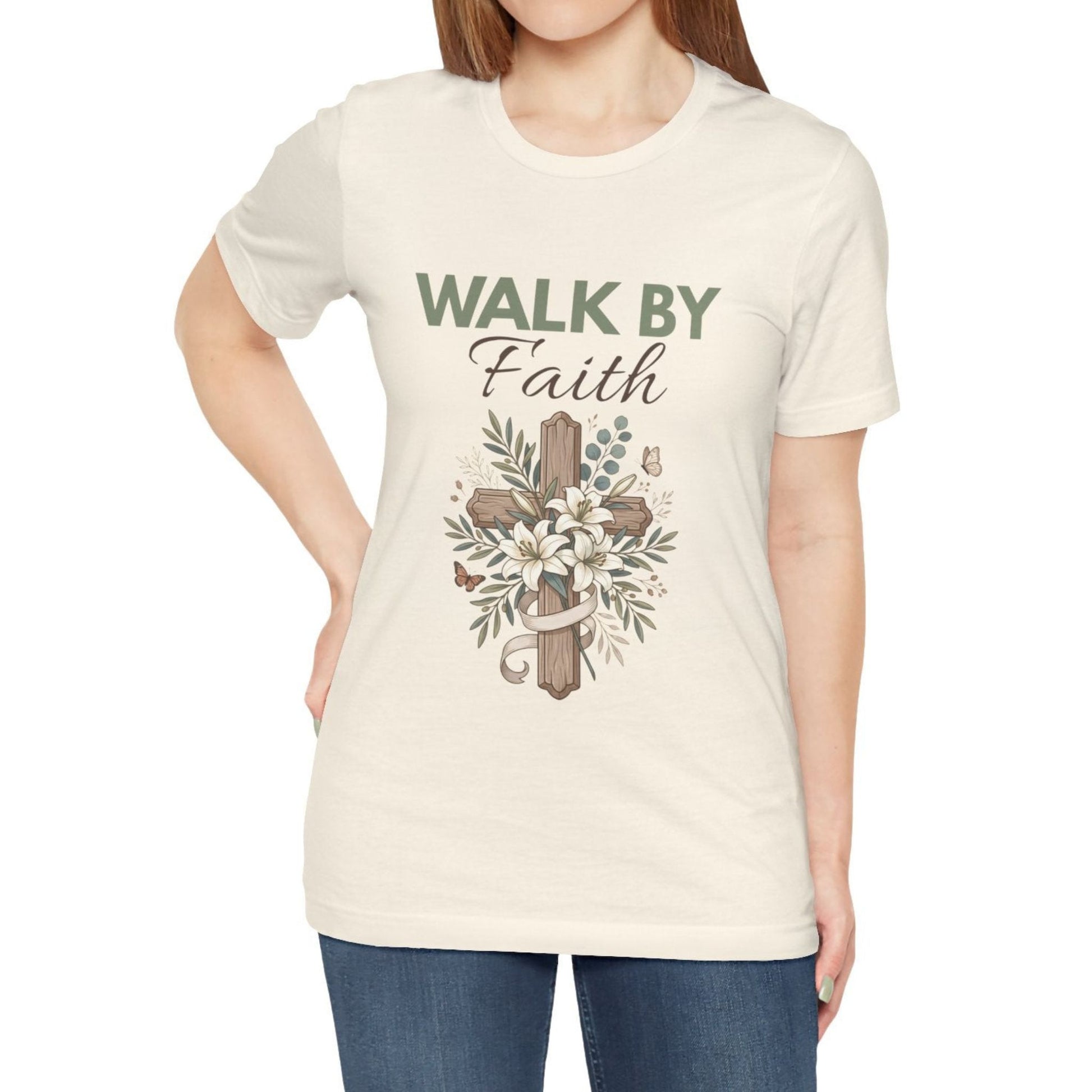 Person wearing a natural colored t-shirt with 'Walk by Faith' design on a white background