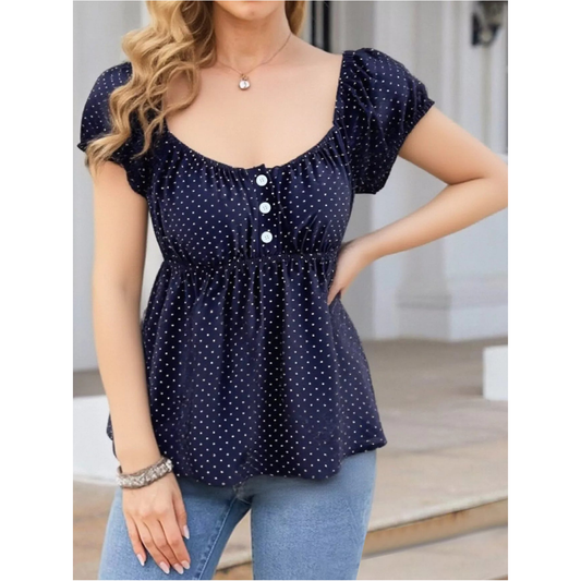 Woman wearing a navy blue polka dot blouse with short sleeves.