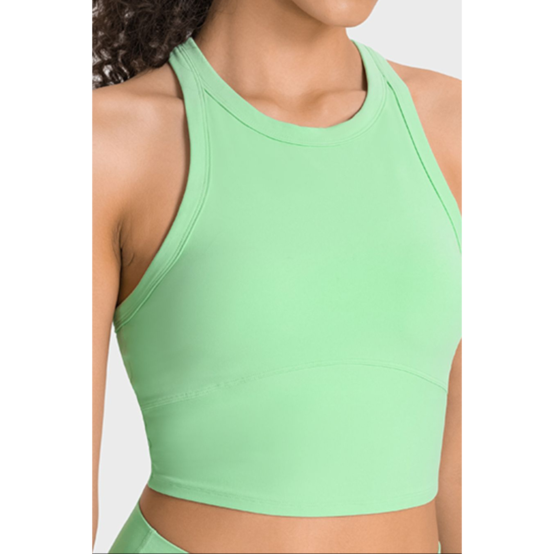Light green sports bra worn by a person on a white background